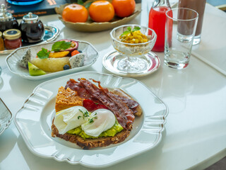Breakfast set, fried egg, bacon, cereal, milk and pastry on elegant ceramic dish, served in luxury hotel