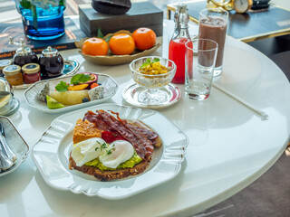 Breakfast set, fried egg, bacon, cereal, milk and pastry on elegant ceramic dish, served in luxury hotel