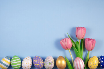 Pink tulips flowers and colourful eggs on blue background. Card for Happy Easter. Waiting for spring. Greeting card. Hello spring and easter concept. fresh tulips. Flat lay, top view, Copy space
