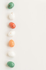 Easter minimal composition with multicolored eggs on the white background. Easter concept. Copy space, flat lay. Vertical photo.