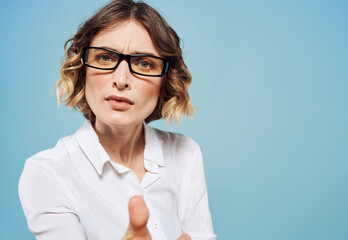 Emotional woman in white shirt puzzled look emotions gesturing with hands blue background