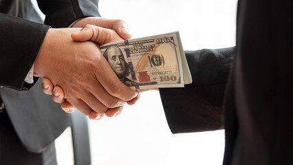 Close-up of two businessmen holding hands together and receiving banknotes in their hands, white background.