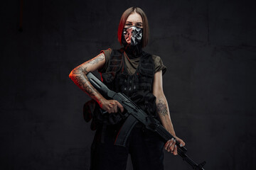 Weared with mask female mercenary holding rifle