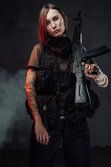 Beautiful female soldier with rifle on her shoulder in smokey background