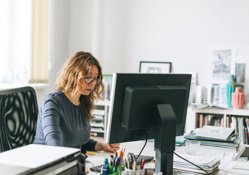 Charming Smiling Adult Woman Middle Aged Woman With Curly Hair Architect Designer Working On Computer In The Bright Modern Office