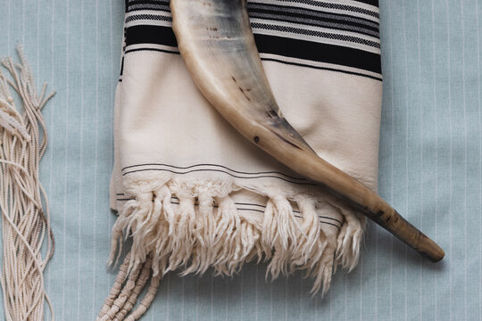 A close-up photo of a shofar and tallit, on a light background