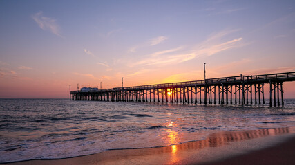 Scenic sunset over the Pacific ocean. A setting sun behind the long pier, Irvine, Orange County,...