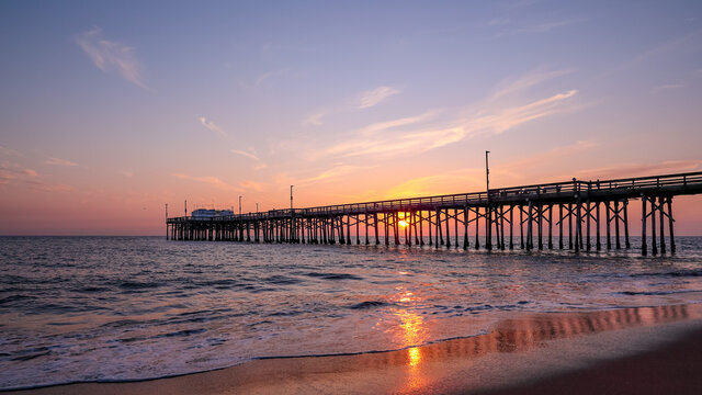 Fototapeta Scenic sunset over the Pacific ocean. A setting sun behind the long pier, Irvine, Orange County, California