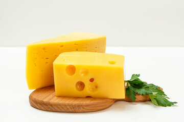 Cheese and parsley on wooden cutting board on white background