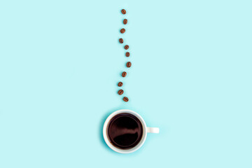 Creative composition: good morning or I love coffee. White cup with black coffee espresso and trickle of steam made from beans on blue background. Caffeine boost drink