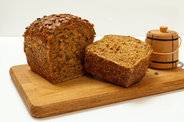 Cut loaf of bread on wooden cutting board on white background