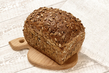 Loaf of bread on wooden cutting board with white wooden background
