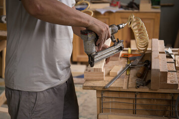 Closeup of a man carpenter using a nail gun.
 - obrazy, fototapety, plakaty