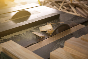 Closeup of wooden planks on a table saw in a workshop with a blurry background 

