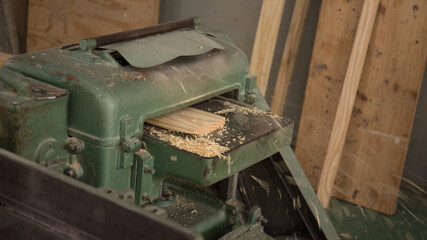 Closeup of a wooden plank in a polishing machine in the workshop with a blurry background

