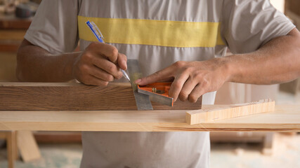 Carpenter measuring wooden board with ruler with scale in workshop. Joinery work on the production...