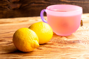 a mug of tea and two lemons on a wooden table