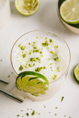 fresh lime juice, lime zest and pineapple. Served in a glass and garnished with a slice of lime.