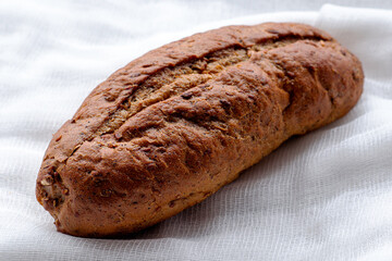 rye freshly baked bread roll on a white cloth napkin