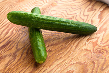 two green cucumbers on the wooden surface of the table