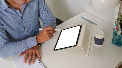 Cropped shot of man freelancer holding stylus pen pointing on screen of digital tablet.