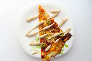 Slice of pizza with olives and sauce on a white plate on a light background