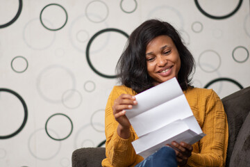 pretty black lady smiling while reading a letter