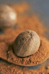 Fototapeta na wymiar Nutmeg spice.Whole and ground nutmeg in a wooden spoon close-up on a black schiffer background.Spices and herbs concept.Food .Spices for meat and baking.Nutmeg powder