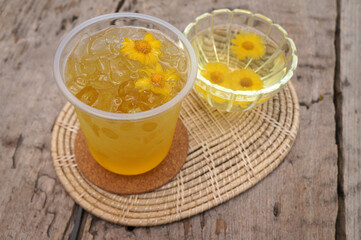 Chrysanthemum juice in a glass placed on a wooden table.