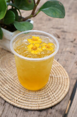 Chrysanthemum juice in a glass placed on a wooden table.