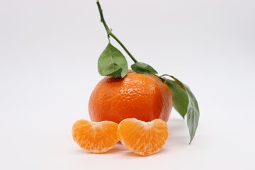 tangerines with leaves and two pieces on white background