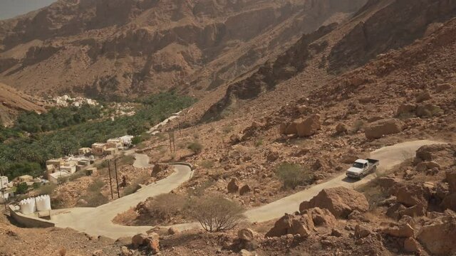 Truck Riding down winding Desert Road to Wadi Tiwi Al Sharqiyah, Oman - Wide Pan Tracking shot
