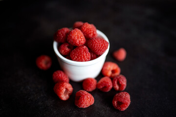 Organic Red raspberry in a bowl, isolated on a black background. Close-up of fresh Red raspberry fruits. Ripe berries bowl. Summer sweet fruits.