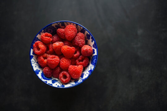 Ripe Red raspberry in a clay bowl on a black background. Flat lay, top view. Photo of Red raspberry in clay bowl on table. High resolution product.