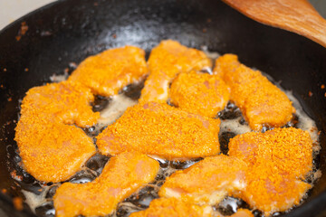 Fried chicken fillet, breaded in a pan.