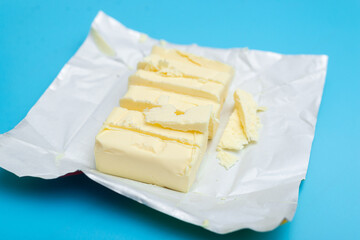 Chopped pieces of butter milk butter on a blue background.