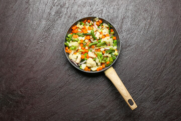 Frying pan with tasty vegetables and chicken on dark background