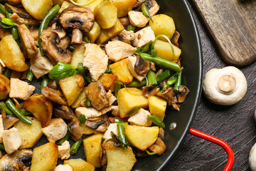 Frying pan with tasty vegetables and chicken on dark background, closeup