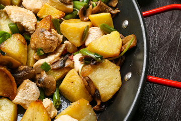 Frying pan with tasty vegetables and chicken on dark background, closeup