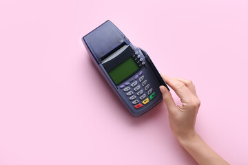 Female hand with credit card and payment terminal on color background