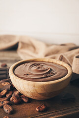 Bowl of tasty melted chocolate on wooden background