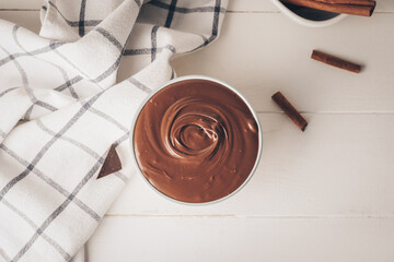 Bowl of tasty melted chocolate on light wooden background