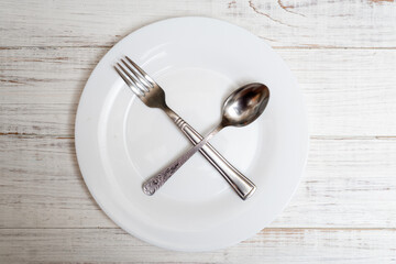The spoon and fork are on an empty plate. Diet concept, intermittent fasting.