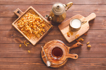 Obraz na płótnie Canvas Cup with hot Turkish tea, raisins and jug of milk on wooden background
