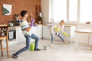 Young couple having fun while cleaning their kitchen