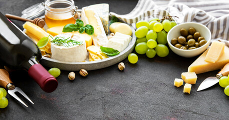 Various types of cheese, grapes, wine and snacks