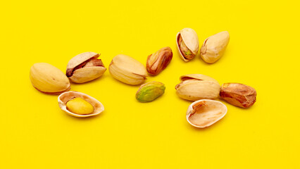 Close-up of fresh pistachio nuts on a yellow background.