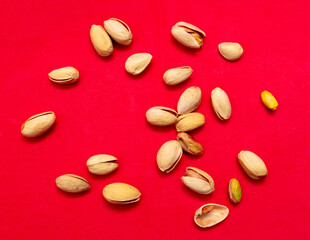 Close-up of fresh pistachio nuts on a red background.