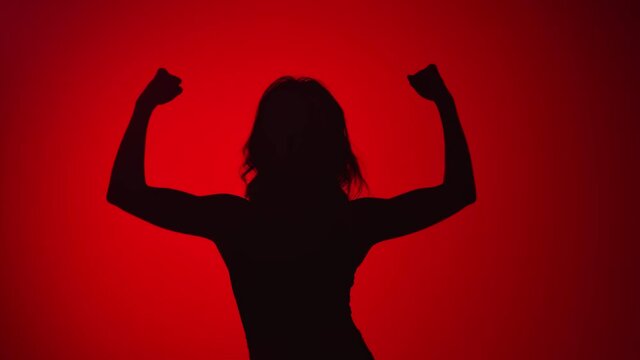 Black silhouette strong athletic woman performing hands muscle at red studio. 4k Dragon RED camera