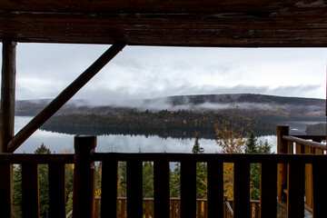 Rive de l'autre côté d'un lac lors d'une journée grise avec des nuages bas vu d'un balcon